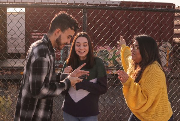 man and two women standing near linked-chain fence