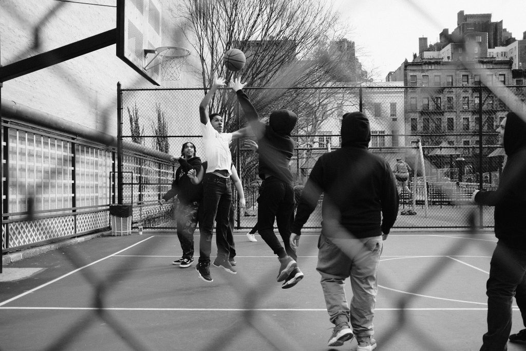grayscale photo of group of men playing street basketball